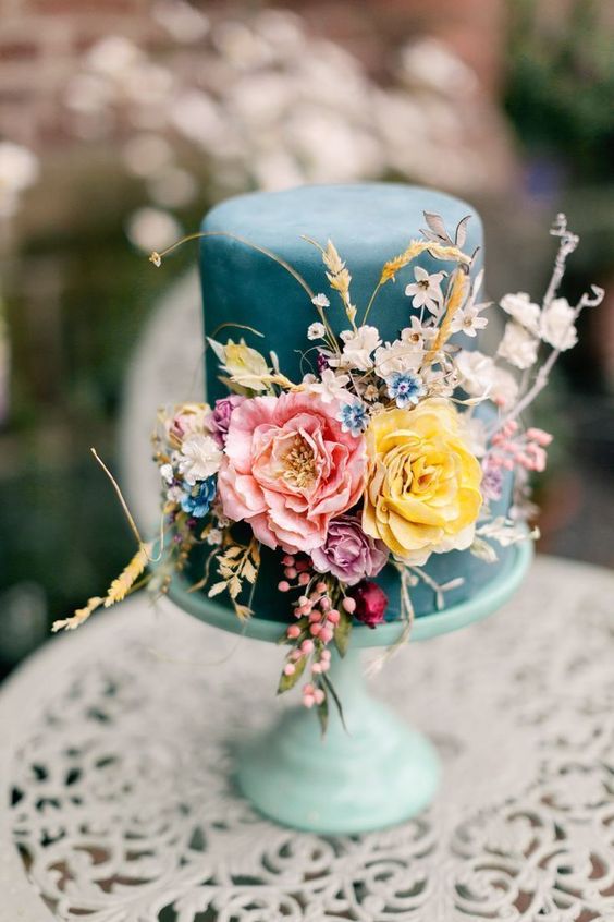 a whimsy blue wedding cake with pink, yellow, lilac, blue blooms, wheat and some neutral blooms, too is amazing