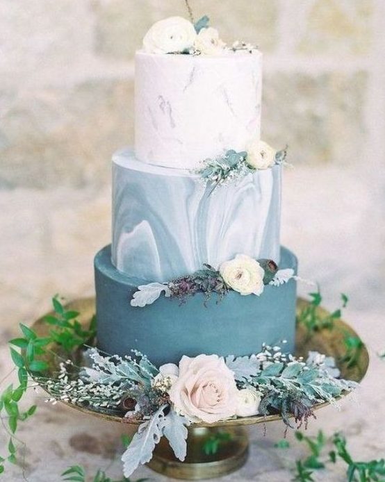 an adorable wedding cake with a plain blue, blue marble and white marble tier, white blooms and pale leaves