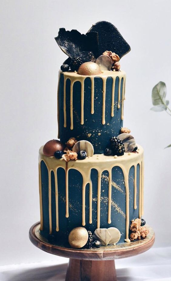 an edgy navy wedding cake with gold drip and gold glitter, with gilded berries, sugar and chocolate marble touches and black shards on top