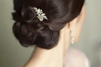 an elegant and laconic wedding updo with a sleek and shiny volume on top and some curls plus an embellished hairpiece is a lovely and bold option to rock