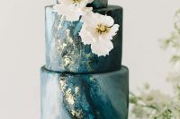 an elegant and refined wedding cake with blue marble tiers, with gold leaf, white sugar blooms is a very beautiful and cool idea