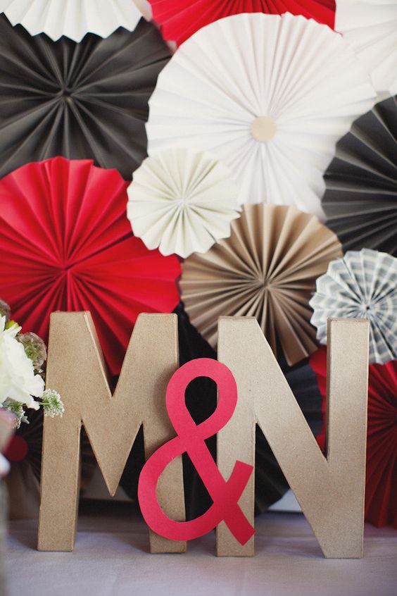 bright wedding decor with white, black and red paper fans of various sizes, with monograms and an ampersand is cool