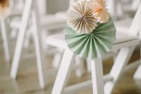 decorate wedding chairs with simple pastel paper fans – that’s cheaper than blooms and easy