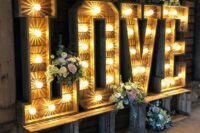 oversized rustic marquee LOVE letters decorated with greeneery and blooms can meet your guests at the entrance