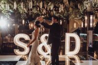 style your dance floor with oversized marquee letters and an ampersand, add greenery and blooms over it