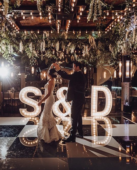 style your dance floor with oversized marquee letters and an ampersand, add greenery and blooms over it