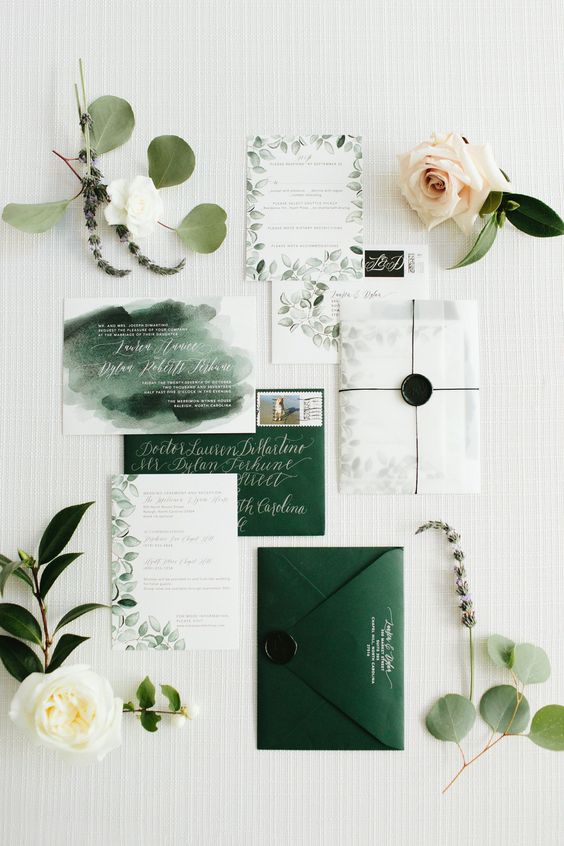 a beautiful wedding invitation suite with hunter green envelopes, white invites with leaves painted and a watercolor calligraphy piece