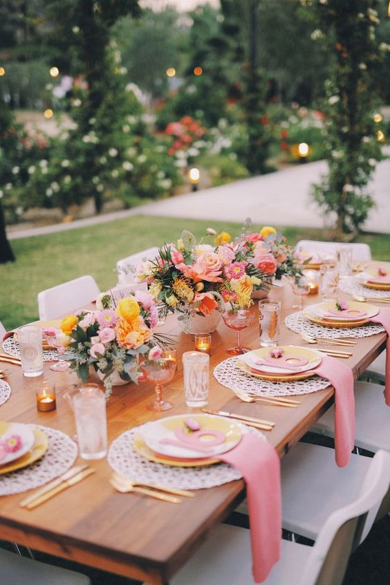 a beautiful wedding tablescape with pink napkins, yellow plates, bold yellow and pale pink wedding centerpieces