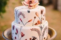 a boho handpainted wedding cake in traditional fall colors topped with a sugar flower is great for fall nuptials