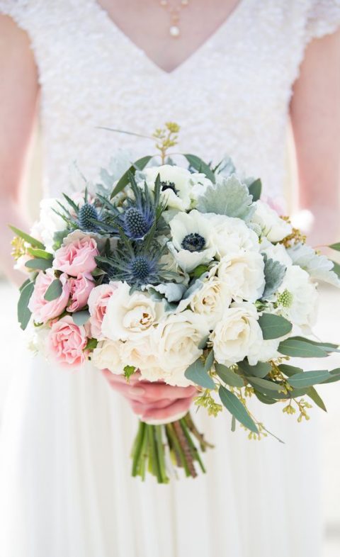 a bouquet with neutral and pink roses, anemones and blue thistles for a spring bride