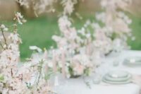 a breathtaking enchanted garden wedding tablescape done in pastel green and blush, with beautiful almond blossom centerpieces and green plates