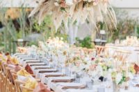 a bright and chic spring wedding reception with bright blooms, greenery, a lush chandelier of pampas grass and blush flowers