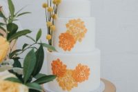 a bright and cool wedding cake in white, with orange and yellow brushstroke flowers and billy balls is a bold idea for a 70s wedding