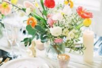 a bright spring wedding table with neutral linens, bright blooms, candles and gold cutlery and chic menus