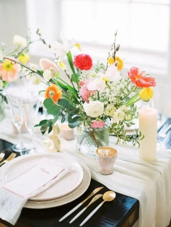 a bright spring wedding table with neutral linens, bright blooms, candles and gold cutlery and chic menus