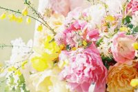 a bright wedding bouquet with pink peonies, yellow and white blooms and foliage is amazing for a spring or summer wedding