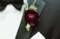 a burgundy ranunculus with greenery is a bold touch of color and interest to the classic black suit