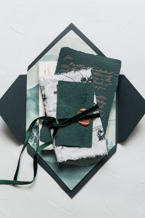 a catchy wedding inivtation suite in white and dark green, with green velvet ribbon and seals and a black envelope