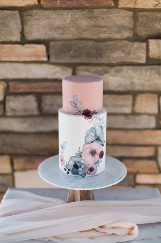 a chic and delicate wedding cake with a dusty pink upper tier and a white one with hand painted flowers on it