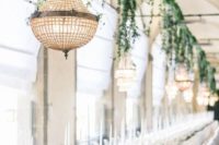 a chic formal wedding reception with greenery decor and chandeliers, white blooms and candles