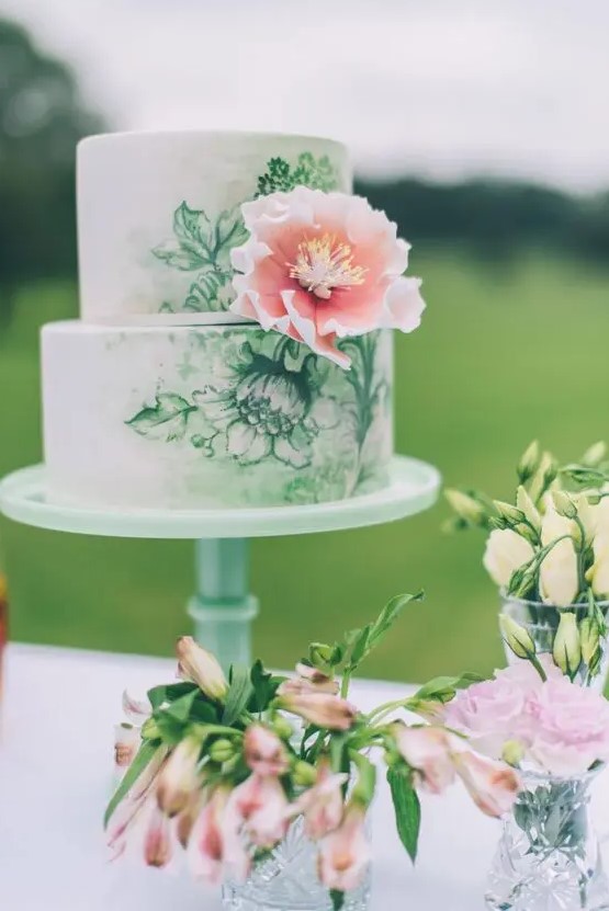 a chic handpainted wedding cake in green and white decorated with a single pink sugar bloom
