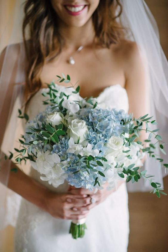 a chic spring wedding bouquet with light blue and white blooms and greenery for a spring bride