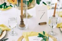 a chic spring wedding tablescape with a lush floral centerpiece, rust candles, lemon yellow napkins and yellow plates