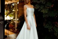 a classic A-line plain wedding dress with thick straps and a square neckline, a pleated full skirt with a train