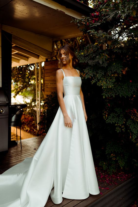 a classic A-line plain wedding dress with thick straps and a square neckline, a pleated full skirt with a train