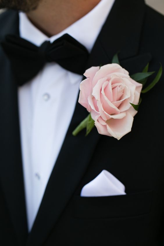 a classic black tux with a bow tie and a blush rose as a boutonniere for a chic and lovely touch of color and to enliven the classic color scheme