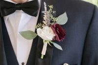 a classic navy tux with black lapels, a white and burgundy ranunculus, greenery and grasses are a chic and stylish combo to rock