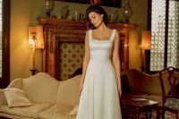 a classic yet modern A-line wedding dress of plain fabric, with an A-line silhouette and a square neckline, thick straps