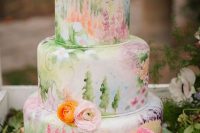 a colorful hand painted wedding cake with tiers showing the sun, blooms, trees and meadows plus colorful flowers is a real masterpiece