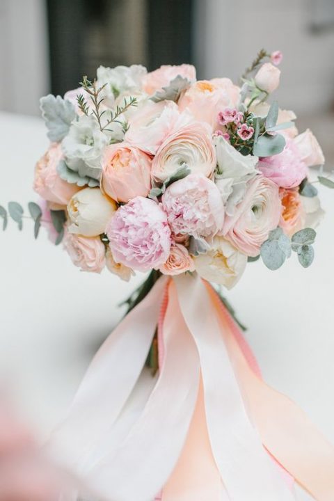 a coral and pink wedding bouquet with pale eucalyptus and pale millet and ribbons is a real eye candy