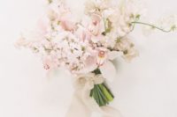 a delicate blush and white wedding bouquet with neutral ribbons and beads for a spring bride