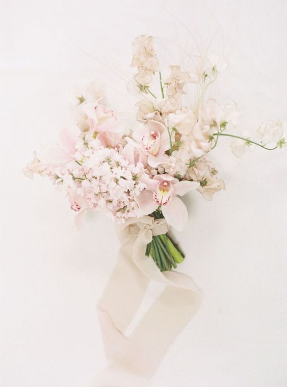 a delicate blush and white wedding bouquet with neutral ribbons and beads for a spring bride