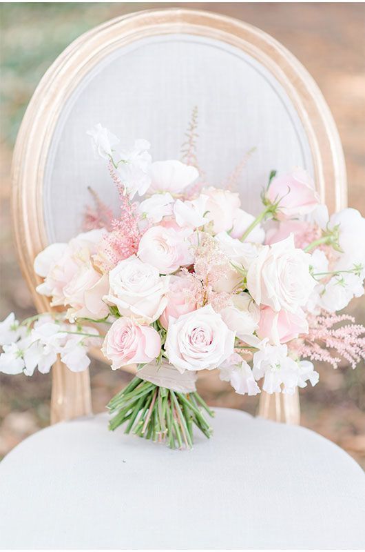 a delicate light pink wedding bouquet with various types of blooms and a simple neutral wrap