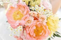 a delicate pastel wedding bouquet of blush, yellow and white blooms and berries plus some leaves for a spring bride