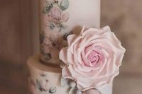 a delicate wedding cake with pastel handpainted blooms and very natural looking pastel sugar blooms