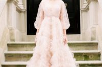 a dreamy blush wedding dress with a tiered tulle skirt and illusion puff sleeves is very romantic