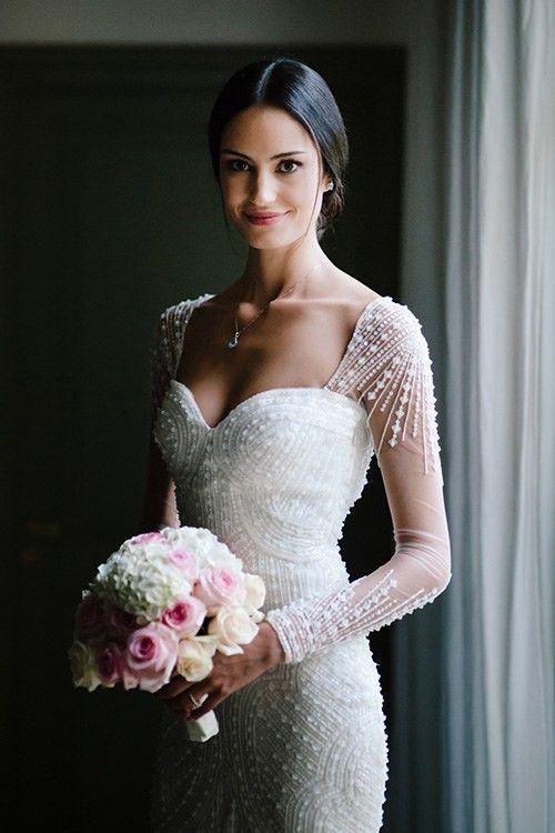 a fitting fully beaded sweetheart neckline wedding dress with illusion sleeves for a glam bride