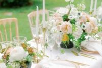 a fresh spring wedding tablescape with pink plates, blush and white blooms, white candles and gold touches
