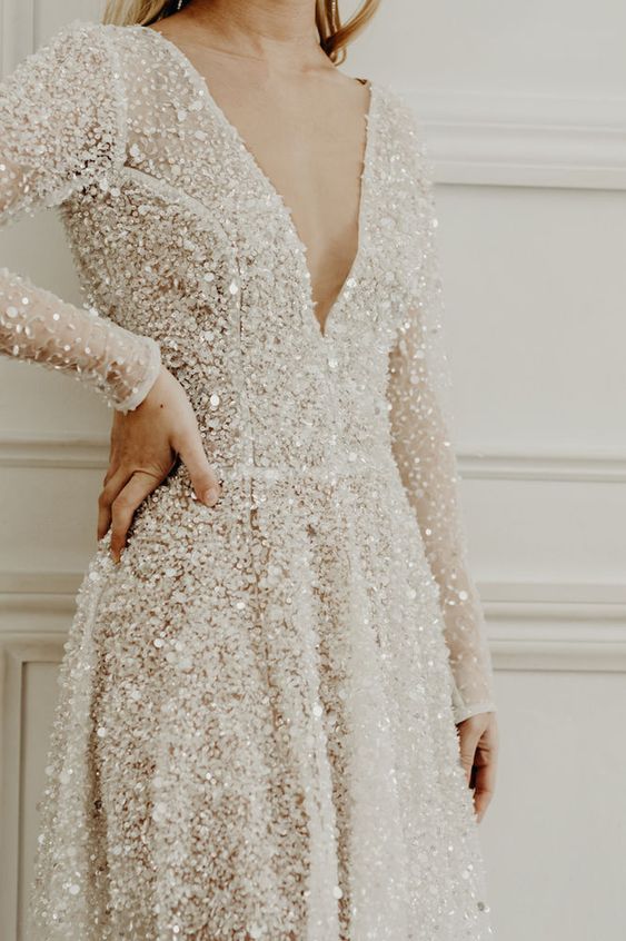 a fully embellished A line wedding dress with a V neckline, long sleeves is a super glam and chic idea
