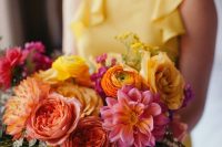 a gorgeous bright wedding bouquet of yellow, orange, coral and pink blooms and greenery and a yellow bridesmaid dress
