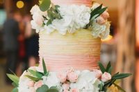 a gorgeous pink and yellow ombre wedding cake decorated with pink and white blooms and foliage looks amazing