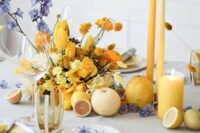 a gorgeous wedding tablescape with a grey tablecloth and napkins, white and gold plates, yellow candles and a yellow floral arrangement