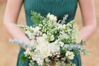 a hunter green halter neckline bridesmaid dress with a pleated bodice and a greenery and white bloom wedding bouquet