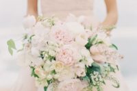 a large blush and cream asymmetrical bridal bouquet with some greenery is a spring statement