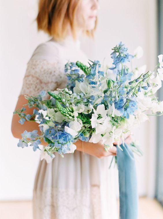 a light blue and white oversized wedding bouquet with some greenery for a spring bride