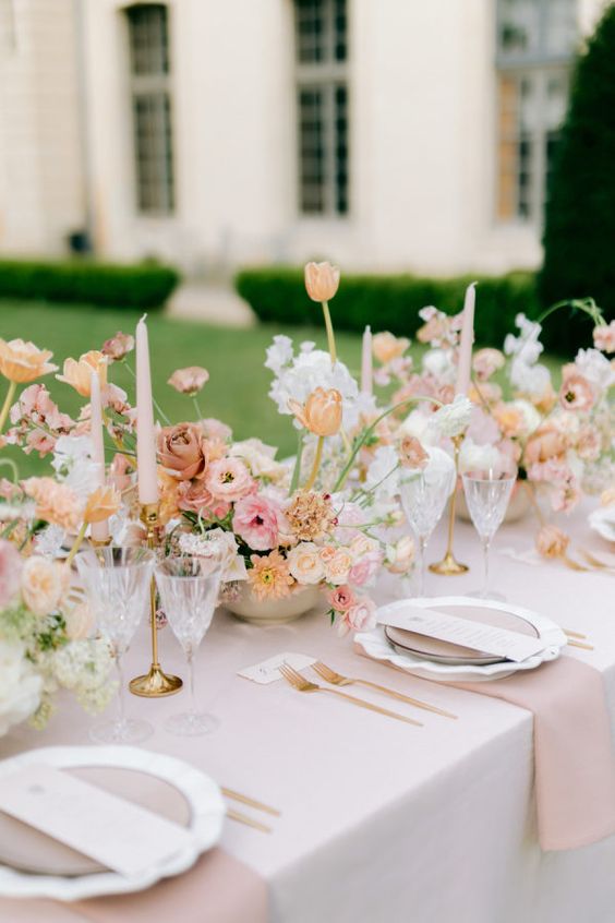 a lovely pastel spring wedding tablescape with blush linens, white, blush and yellow blooms and pink candles is chic